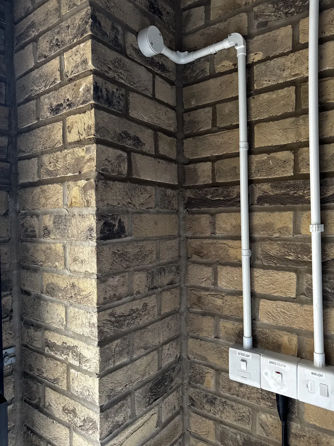 Fused spur and PVC conduit for an outside light installation on a garage wall in Corby