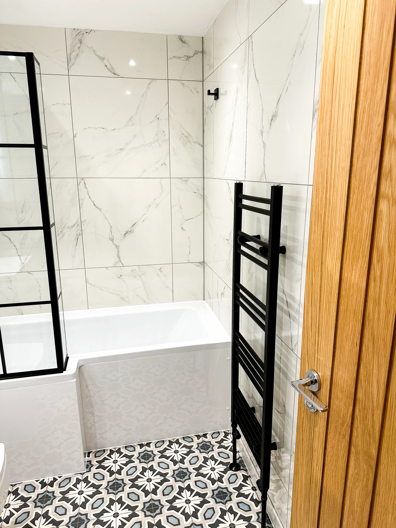 Walk-in shower with large-format tiles in a luxury bathroom renovation by Entigen