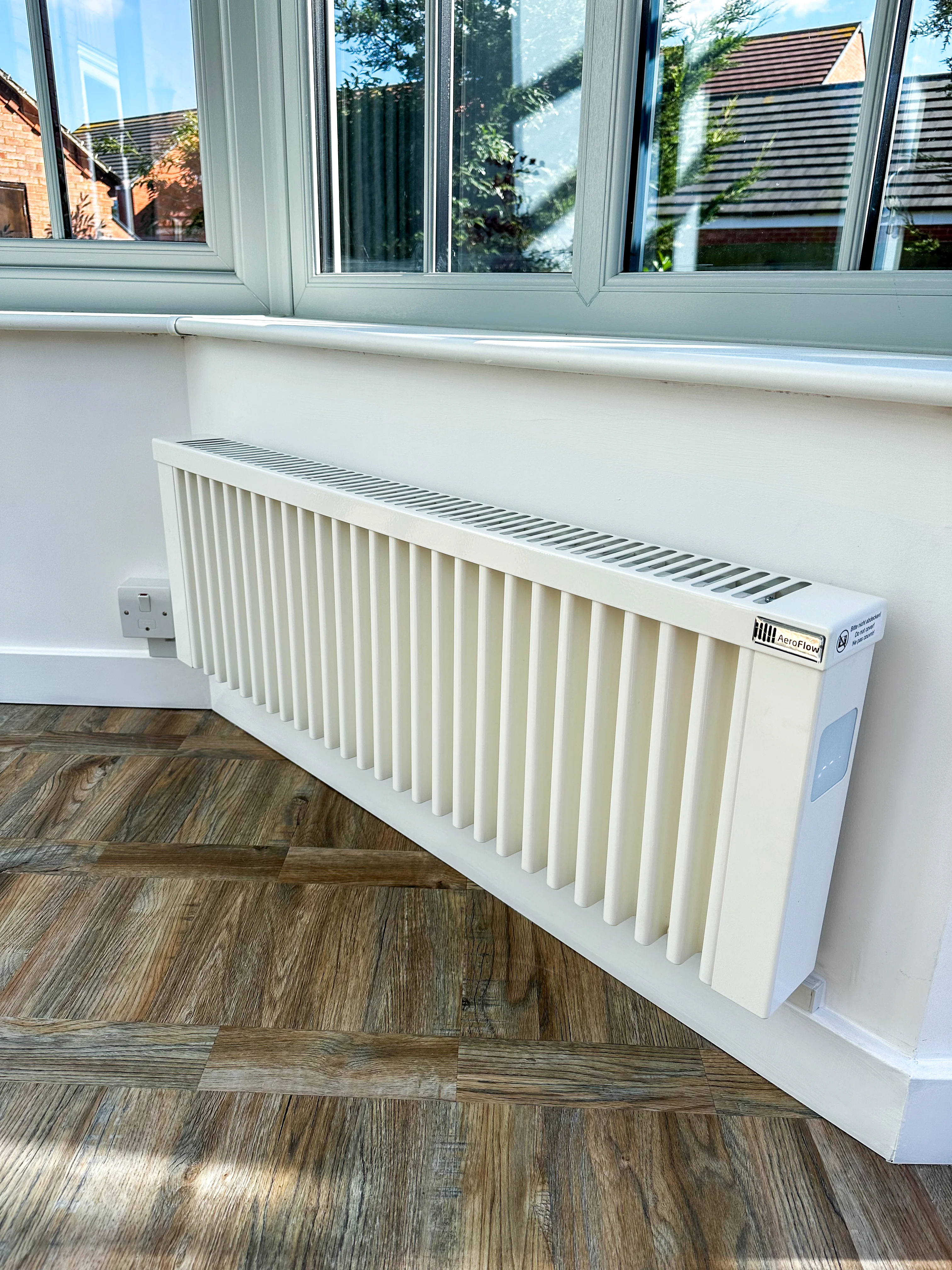 Wall-mounted electric radiator below a window