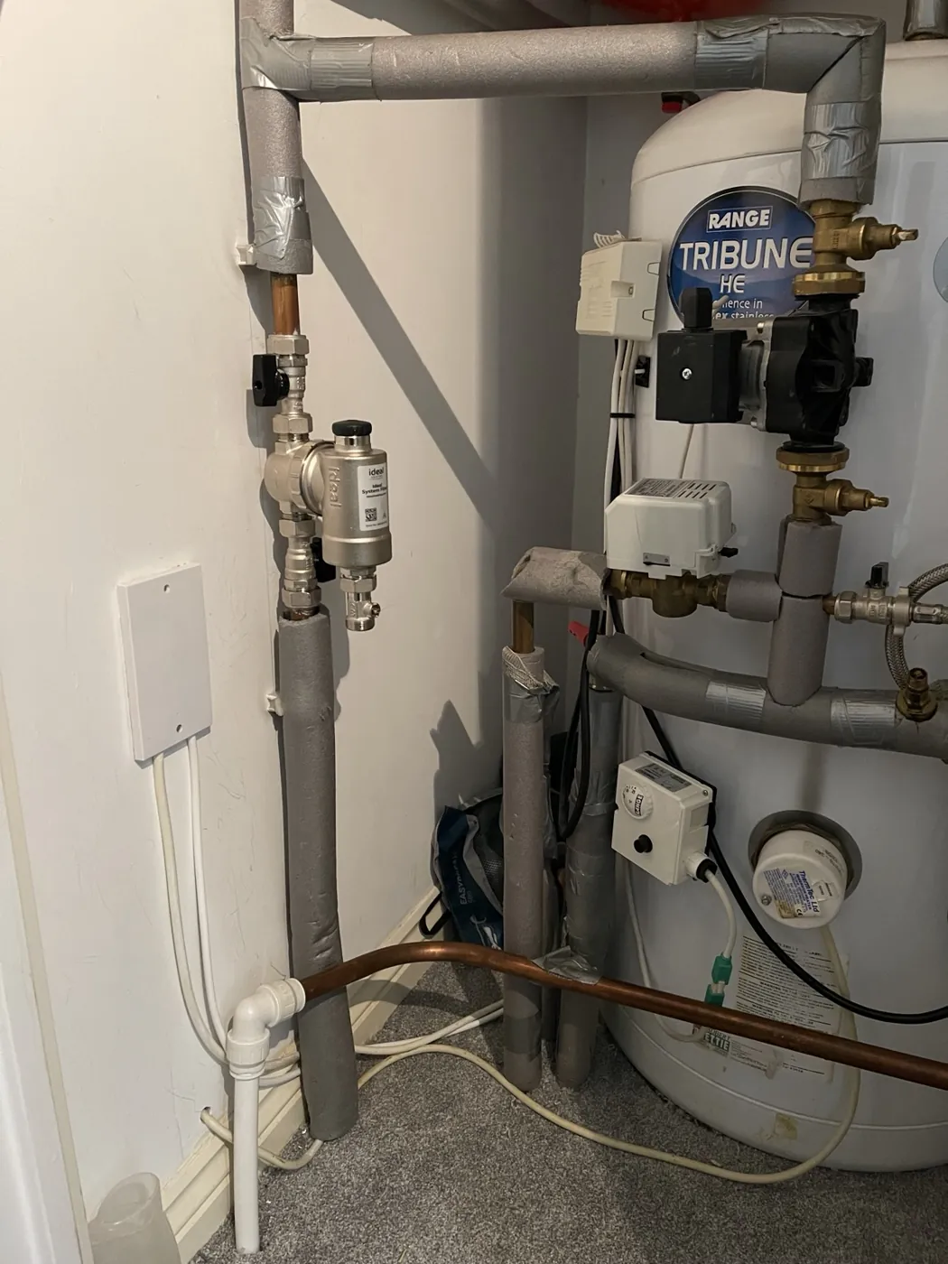 Heating controls electrician inspecting motorised valves and hot water cylinder controls in Northamptonshire